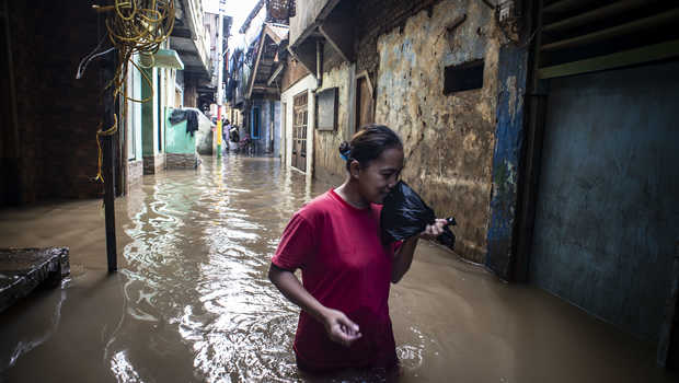 
 Seorang warga saat melintasi genangan air yang melintasi pemukiman warga.(Istimewa/Bogordaily.net)