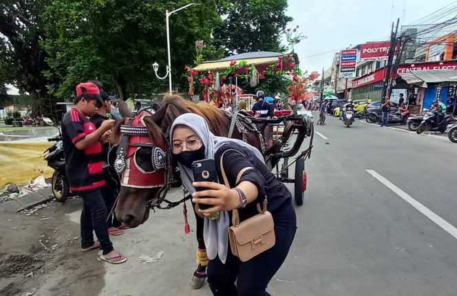 
 Salah seorang penumpang foto bersama delman di Alun-Alun Kota Bogor. (Irfan/Bogordaily.net)